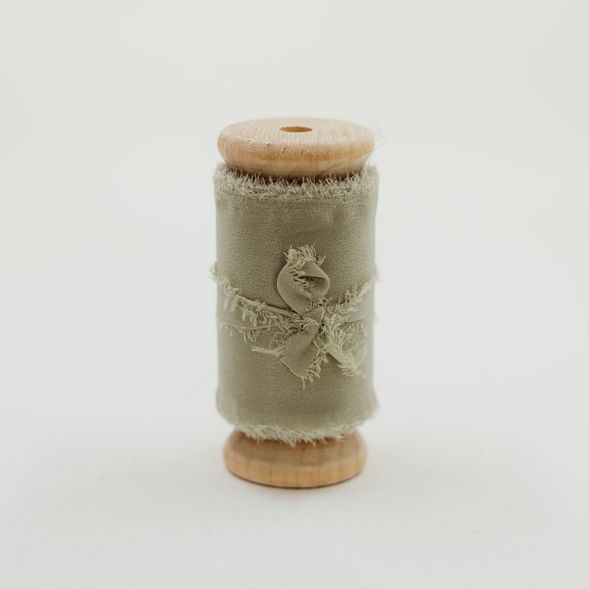 Spool of raw edge silk ribbon in sage color for wedding