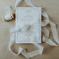 Raw edge, hand-dyed silk ribbon, shown wrapped around a wedding invitation in a styled flat lay, highlighting its handmade quality