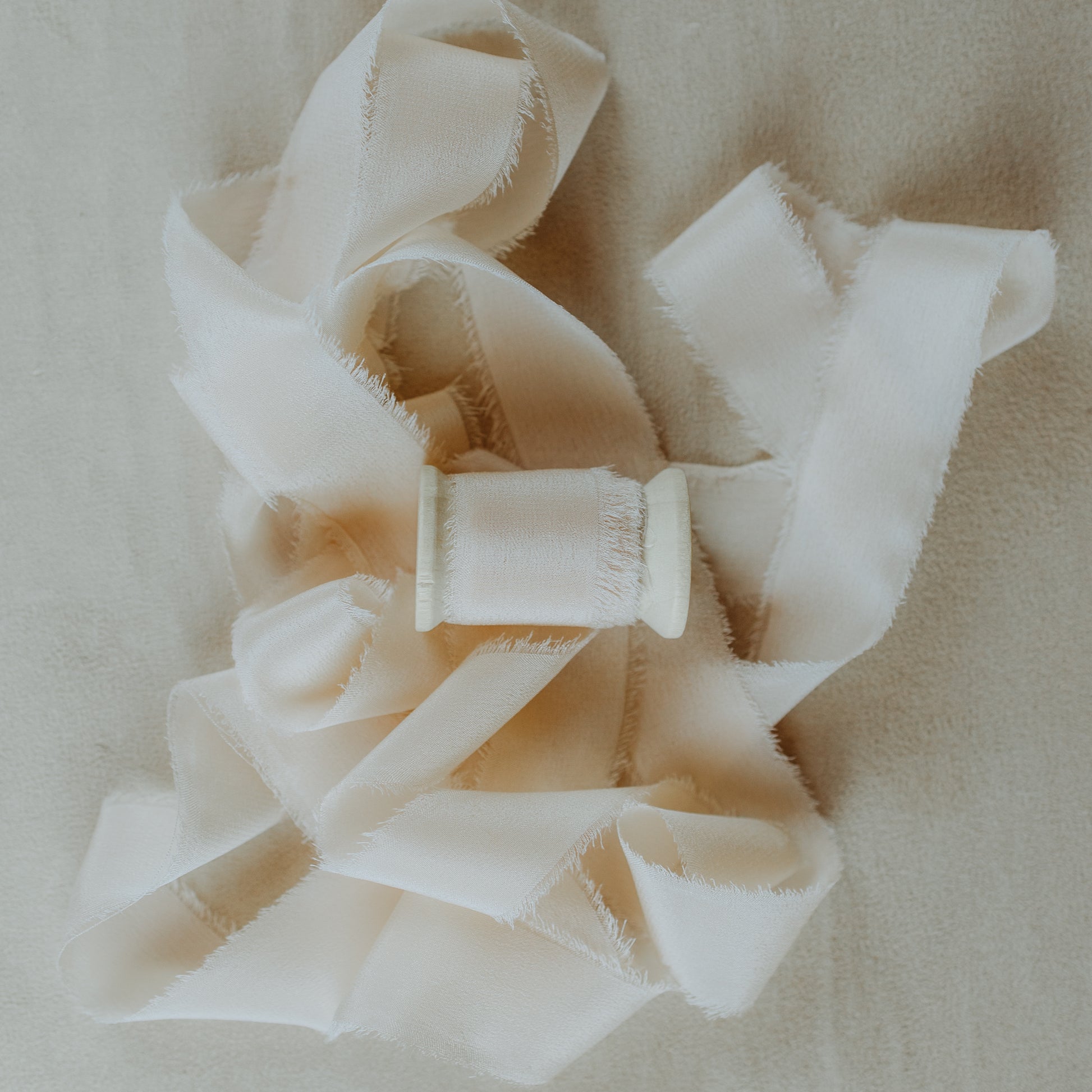 Raw edge silk ribbon, hand-dyed, used to style wedding invitation suites for flat lay photography, showcasing its textured detail