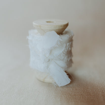 Silk ribbon, hand-dyed and featuring a raw edge, used as a styling element in flat lay images focusing on bridal details and florals