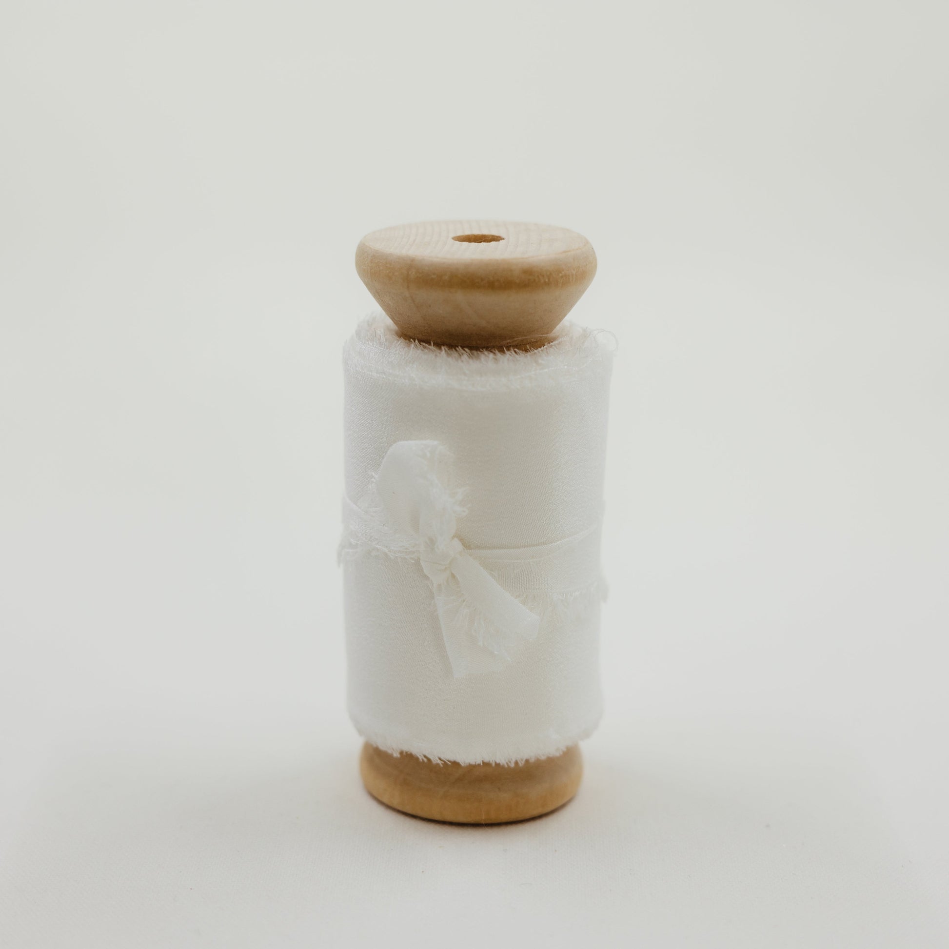 Handmade silk ribbon with a raw edge, used to create soft, flowing lines in bridal flat lay compositions